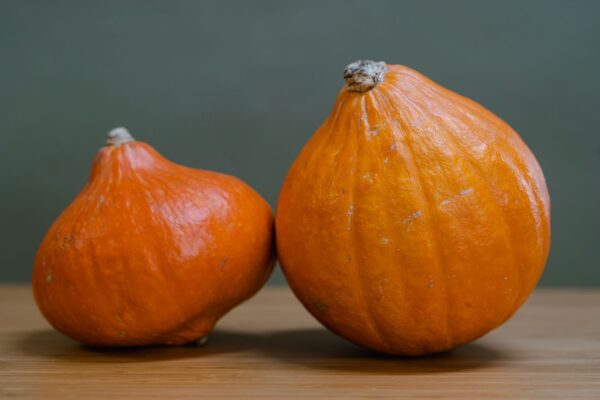 Vibrant orange pumpkins resting on a wooden table, ideal for autumn themes.