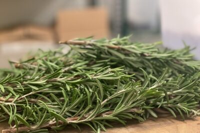 a pile of rosemary on a wooden cutting board