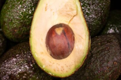 A cut avocado with its seed on a pile.